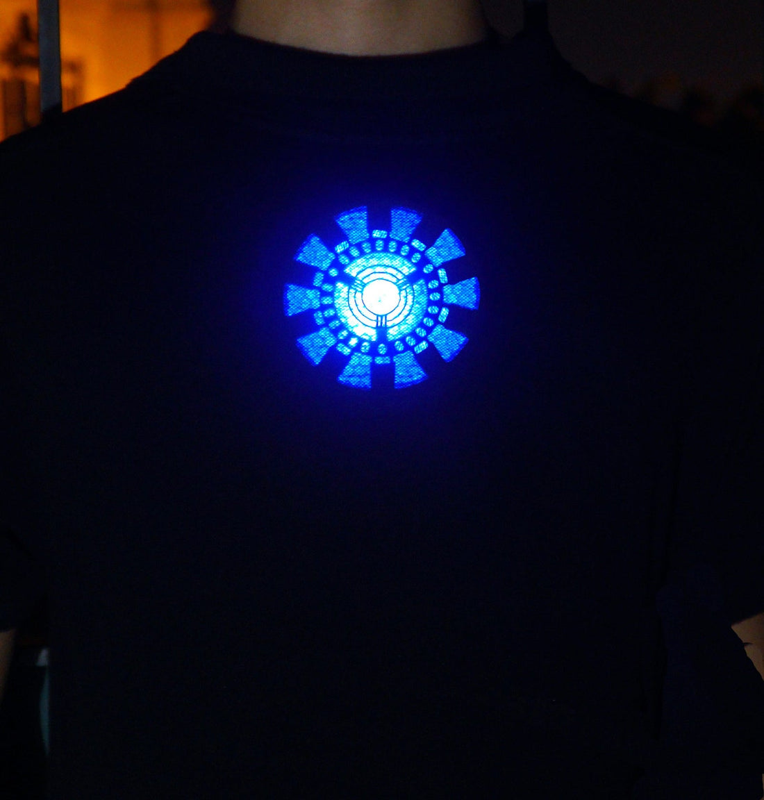 Circular blue arc reactor light pattern visible through a dark shirt