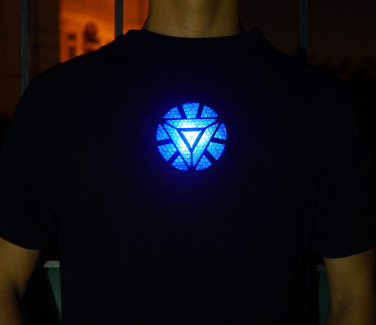 Blue open-triangle arc reactor pattern shining through a dark shirt